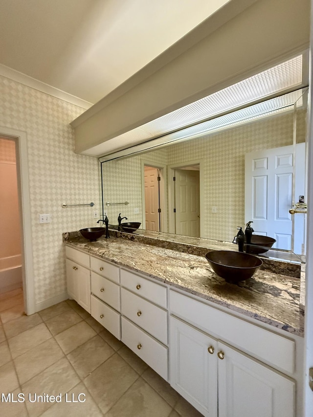 bathroom with tile patterned floors, double vanity, a sink, and wallpapered walls