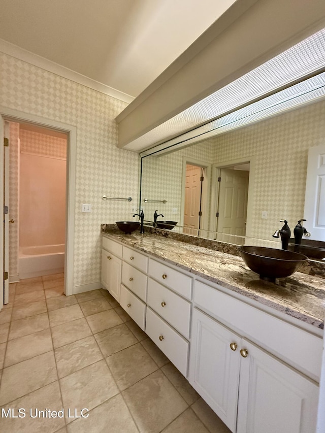 bathroom with double vanity, a sink, and wallpapered walls