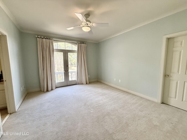 carpeted empty room featuring french doors, crown molding, and baseboards