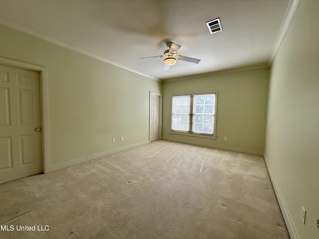 spare room with light colored carpet, a ceiling fan, baseboards, visible vents, and crown molding