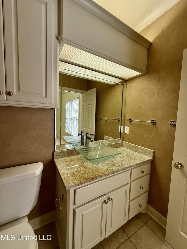 half bathroom with toilet, tile walls, baseboards, vanity, and tile patterned floors