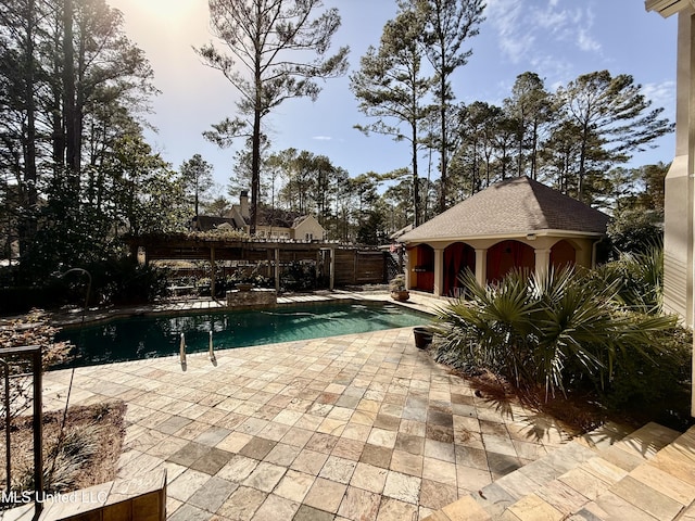 pool with an outbuilding, a patio area, and fence