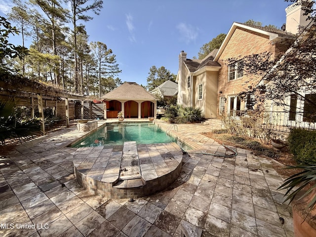 outdoor pool featuring an outbuilding, a patio area, and fence