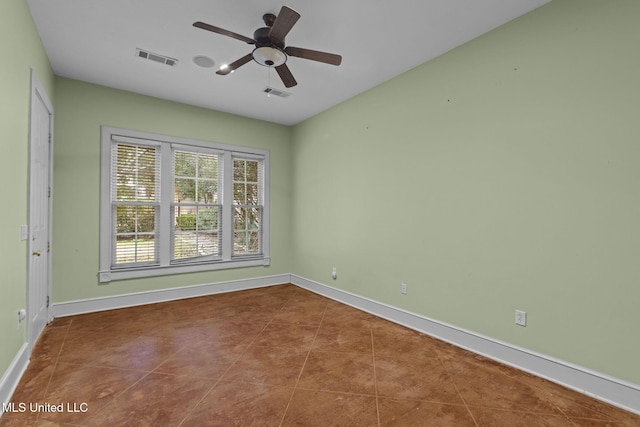 tiled spare room featuring visible vents, ceiling fan, and baseboards