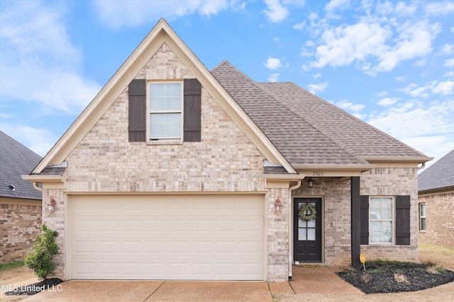 view of front of house featuring a garage, concrete driveway, roof with shingles, and brick siding