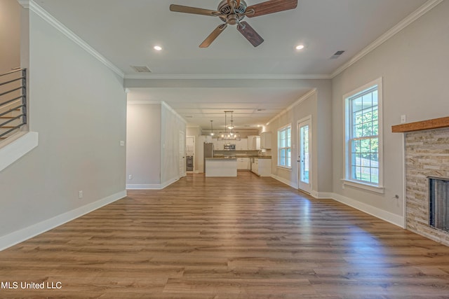 unfurnished living room with ceiling fan, crown molding, a stone fireplace, and hardwood / wood-style floors