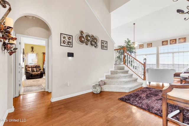foyer entrance with arched walkways, wood finished floors, baseboards, and stairs