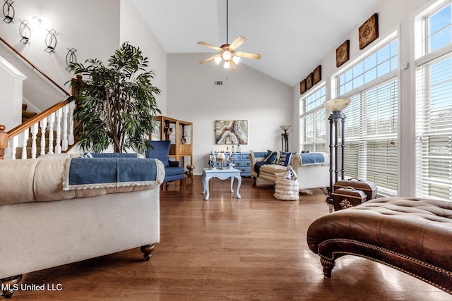 living room featuring healthy amount of natural light, a ceiling fan, high vaulted ceiling, wood finished floors, and stairs