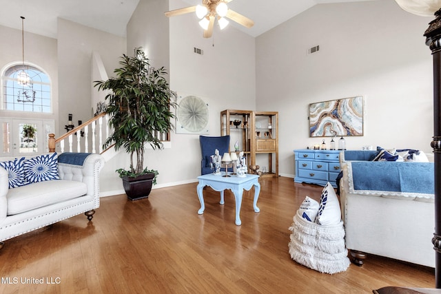 living area with high vaulted ceiling, ceiling fan, wood finished floors, a chandelier, and baseboards