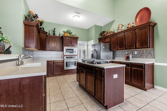 kitchen with a sink, stainless steel appliances, backsplash, and a center island