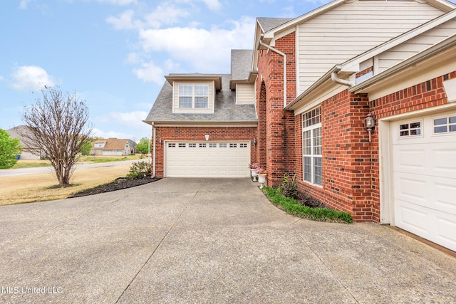 view of side of home featuring driveway, brick siding, a garage, and roof with shingles
