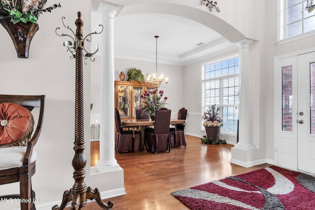 entrance foyer with arched walkways, healthy amount of natural light, wood finished floors, and decorative columns