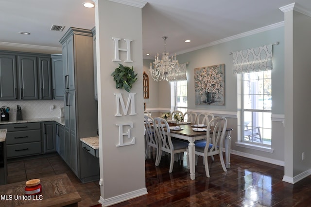 kitchen featuring pendant lighting, gray cabinets, ornamental molding, tasteful backsplash, and light stone counters