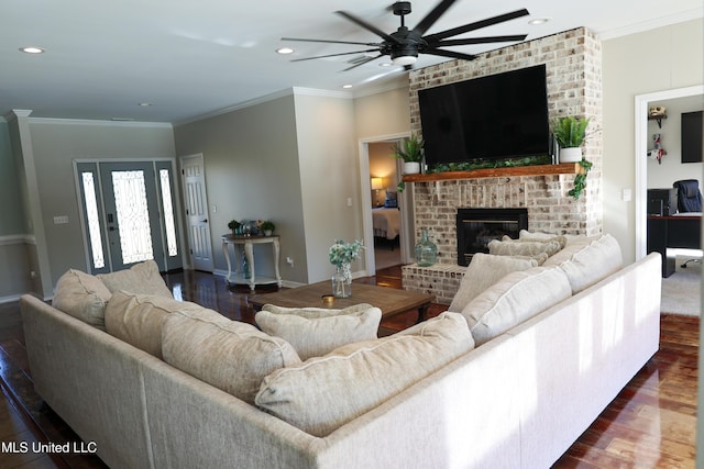 living room with crown molding, dark hardwood / wood-style flooring, ceiling fan, and a brick fireplace