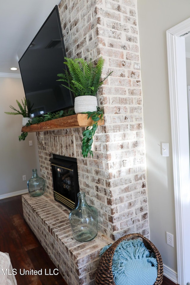 interior details with ornamental molding, wood-type flooring, and a brick fireplace