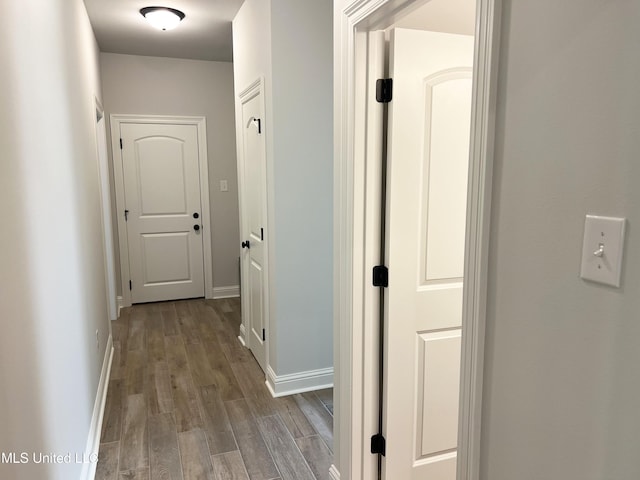 corridor with wood finished floors and baseboards