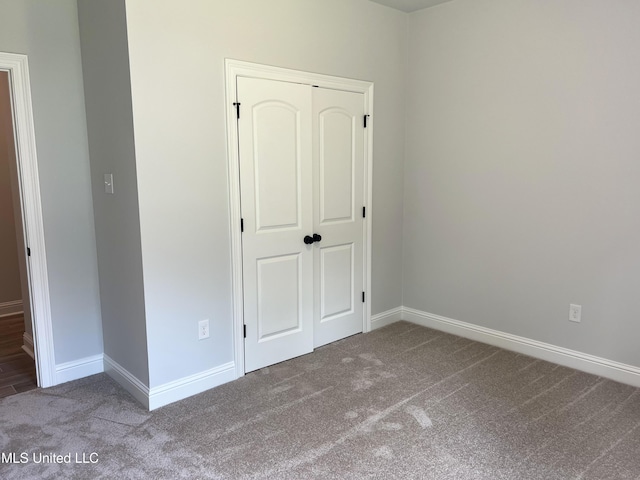 unfurnished bedroom with a closet, carpet flooring, and baseboards