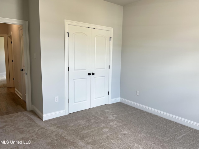 unfurnished bedroom with a closet, carpet, and baseboards