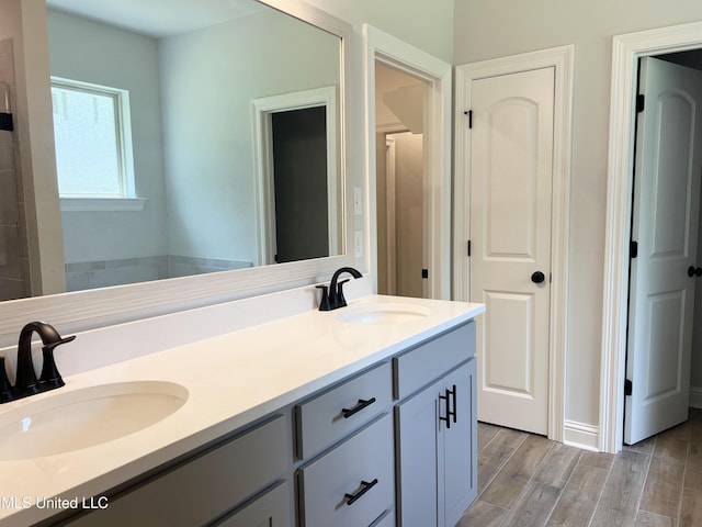 full bath with double vanity, a sink, and wood finished floors