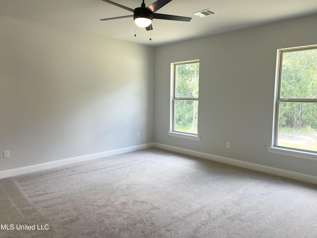 carpeted empty room featuring visible vents, ceiling fan, a healthy amount of sunlight, and baseboards