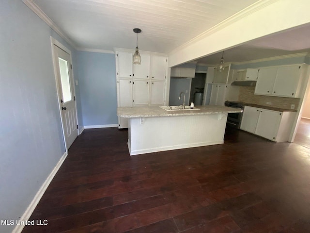 410 N Brooks St, Pelahatchie, MS 39145 - kitchen featuring ornamental molding, under cabinet range hood, dark wood finished floors, white cabinets, and hanging light fixtures