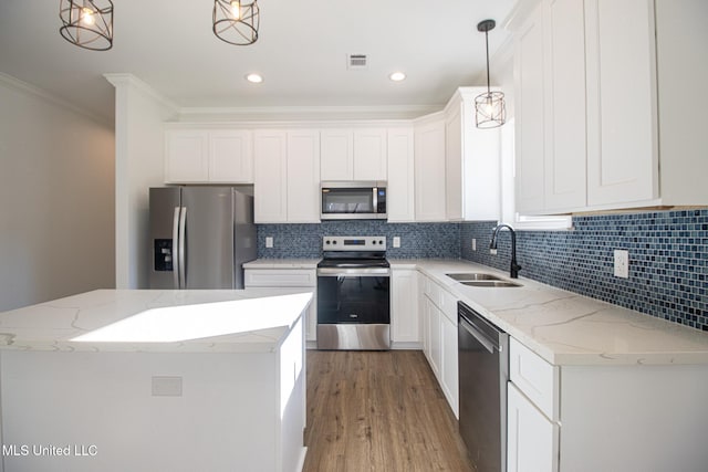 kitchen with white cabinetry, sink, a center island, hanging light fixtures, and appliances with stainless steel finishes