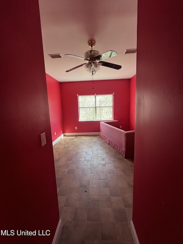 empty room featuring baseboards, visible vents, and a ceiling fan