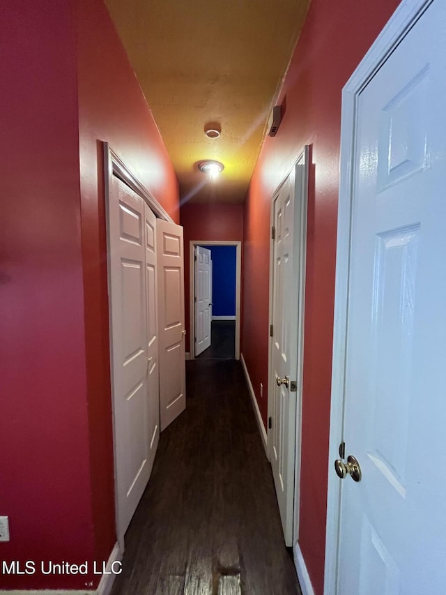 corridor featuring dark wood-style flooring and baseboards