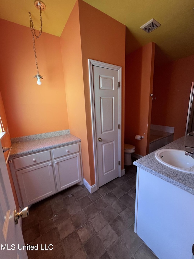 bathroom with baseboards, visible vents, vanity, and toilet