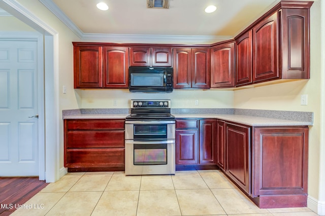 kitchen with double oven range, visible vents, black microwave, reddish brown cabinets, and light countertops