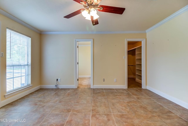 unfurnished bedroom featuring light tile patterned floors, a spacious closet, a closet, and crown molding