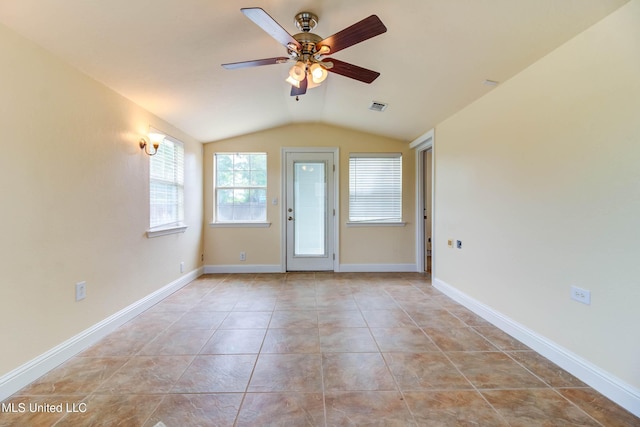 tiled empty room featuring lofted ceiling, baseboards, visible vents, and a ceiling fan