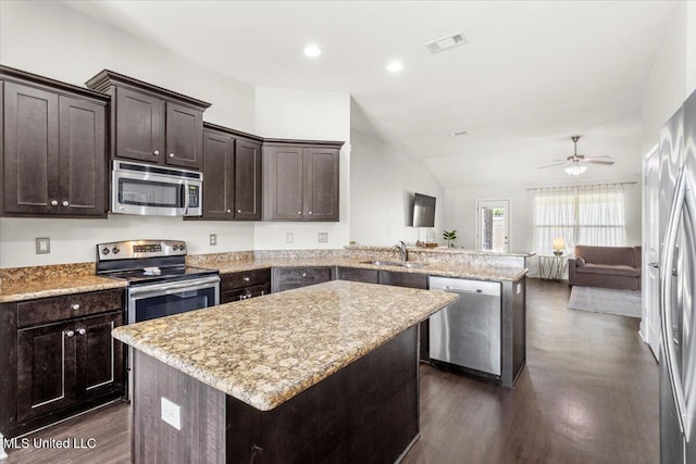 kitchen with a center island, kitchen peninsula, sink, dark brown cabinetry, and appliances with stainless steel finishes