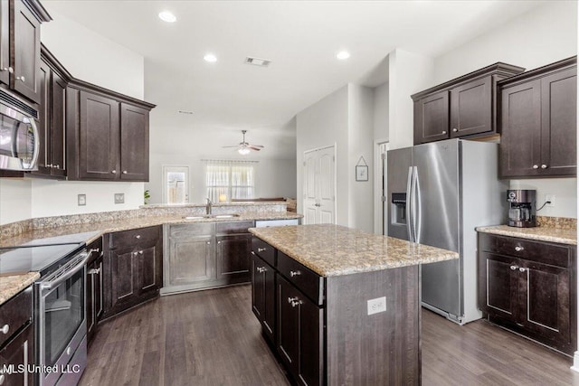 kitchen featuring kitchen peninsula, stainless steel appliances, dark wood-type flooring, a kitchen island, and sink