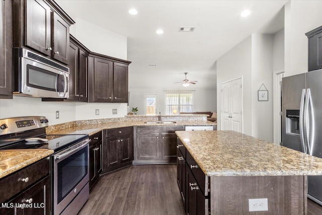 kitchen with appliances with stainless steel finishes, a center island, sink, dark hardwood / wood-style floors, and kitchen peninsula