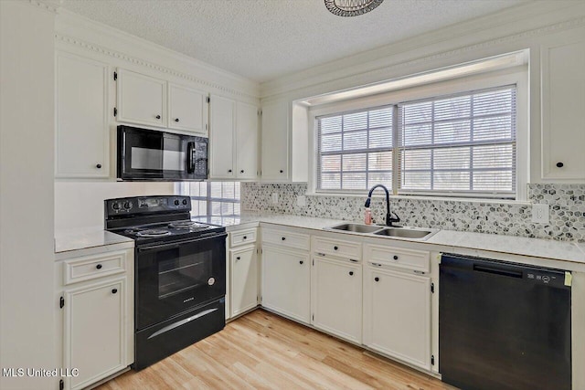 kitchen featuring black appliances, light countertops, light wood-style floors, white cabinetry, and a sink