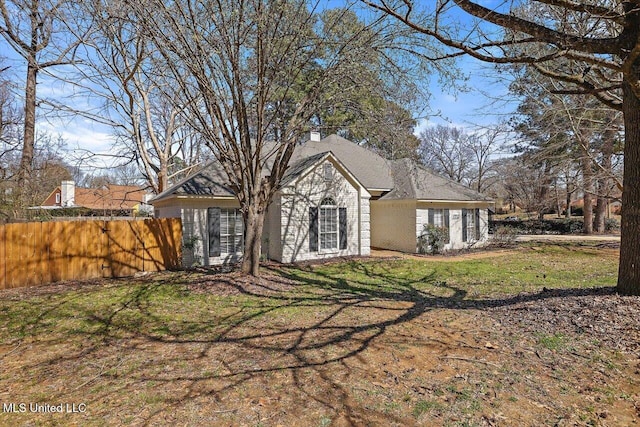 exterior space featuring a chimney, a front lawn, and fence