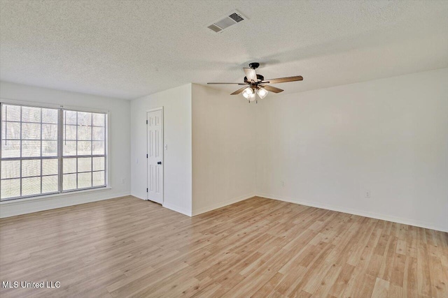 spare room with visible vents, baseboards, ceiling fan, light wood-style floors, and a textured ceiling