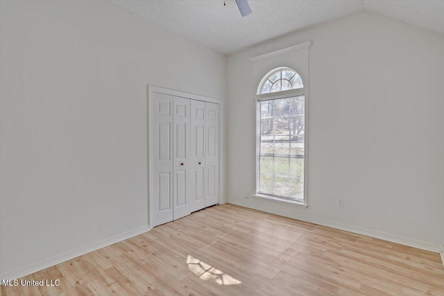 unfurnished bedroom with multiple windows, a textured ceiling, light wood-type flooring, and baseboards