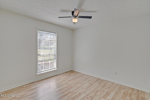 spare room featuring a textured ceiling, baseboards, and wood finished floors