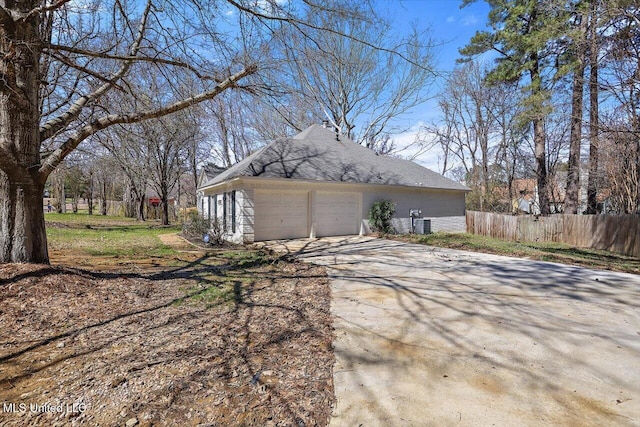 view of property exterior with an attached garage, driveway, and fence