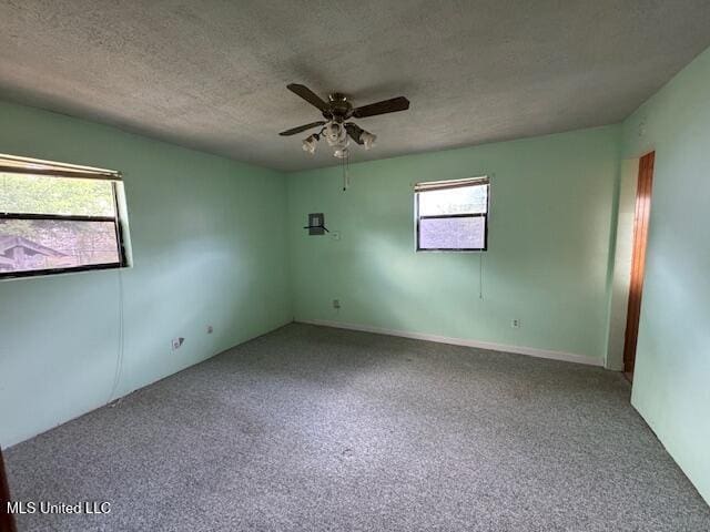 carpeted spare room with a ceiling fan and a textured ceiling