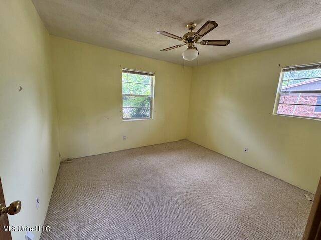carpeted spare room with a textured ceiling and ceiling fan