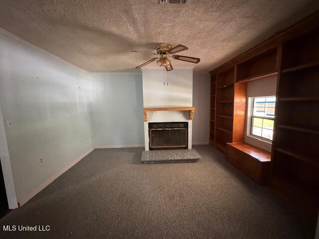 unfurnished living room with a fireplace with raised hearth, a textured ceiling, carpet, a ceiling fan, and baseboards