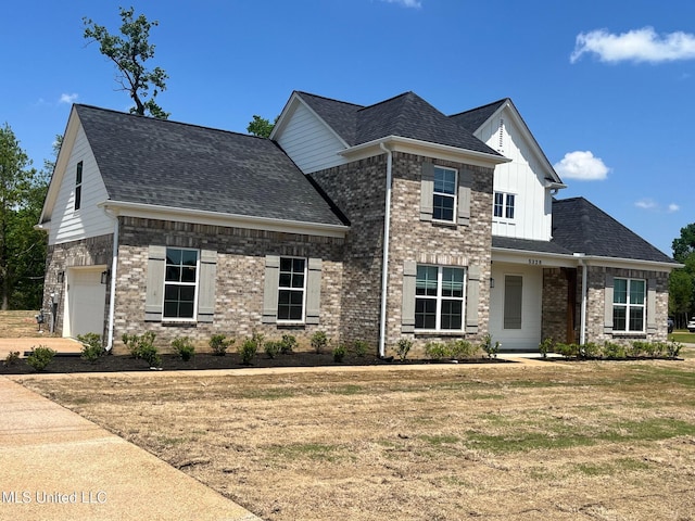 view of front of home featuring a garage, roof with shingles, board and batten siding, a front yard, and brick siding
