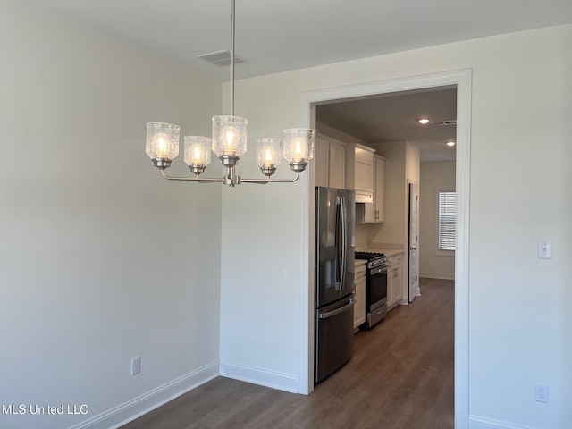 kitchen with appliances with stainless steel finishes, a chandelier, dark wood-style flooring, and baseboards
