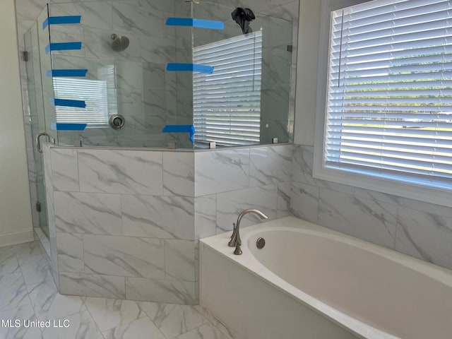 bathroom with marble finish flooring, a shower stall, and a garden tub