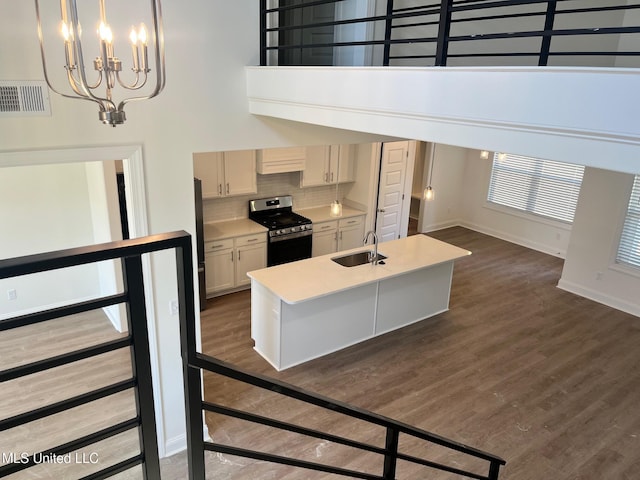 kitchen with stainless steel gas stove, a sink, a chandelier, light countertops, and baseboards