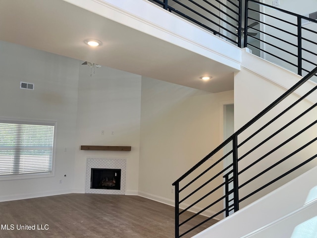 unfurnished living room with a high ceiling, stairs, baseboards, wood finished floors, and a fireplace