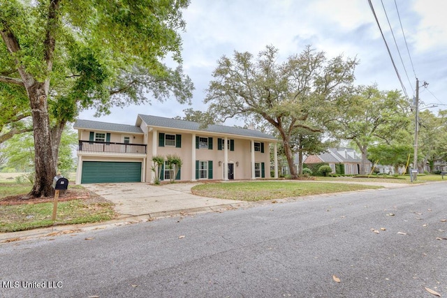 view of front of home featuring a garage, a balcony, and a front yard